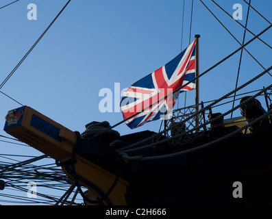 Der Union Jack fliegt aus dem Jack Personal der HMS Victory. Die weltweit älteste beauftragte Kriegsschiff. Rote weiße blaue Flagge auf blauem Himmel Stockfoto