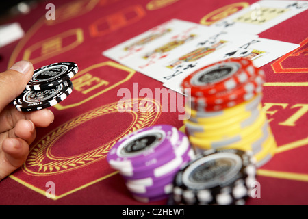 Bild von schwarzen Chips in der Hand über Casino-Tisch Stockfoto