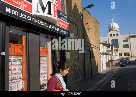 Eine Frau kreuzt die Straße in der Nähe von einem Sikh-Tempel in Southall. Stockfoto