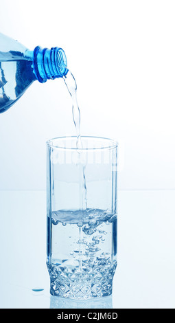 Wasser aus der Flasche in ein Glas beleuchtet Stockfoto