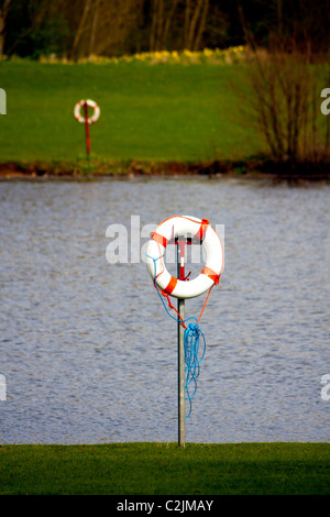 Zwei Rettungsringe Bojen auf gegenüberliegenden Seiten eines Sees, für Sicherheit und Leben zu retten. Stockfoto