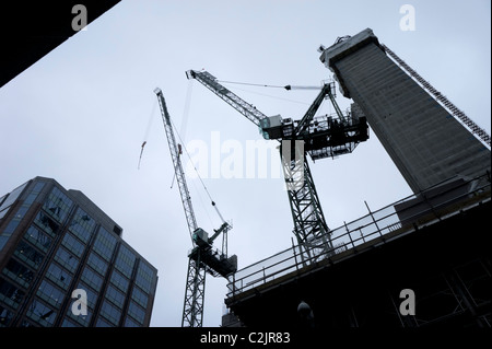 Silhouette niedrigen Winkel Blick auf Baukräne an einem bewölkten Tag Stockfoto