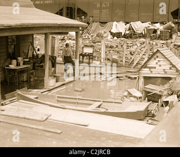 Kanus im Überfluss wie Hochwasser am Ufer unter Betonbrücke und neben Eisenbahnwaggons Trichter Runde. Stockfoto