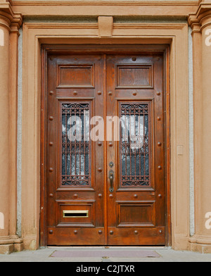 Reich verzierte gefärbten Holztüren mit schmiedeeisernen Gitter über Glasfenster Stockfoto