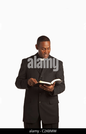 Ein Mann mit einem klerikal-Kragen und lesen aus der Bibel Stockfoto