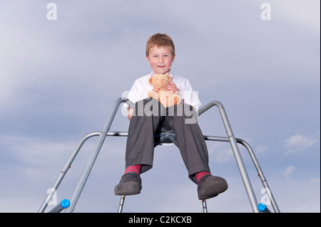 Ein MODEL Release Bild ein sieben Jahre alter Junge und sein Kuscheltier im Freien auf einem Klettergerüst im Vereinigten Königreich Stockfoto