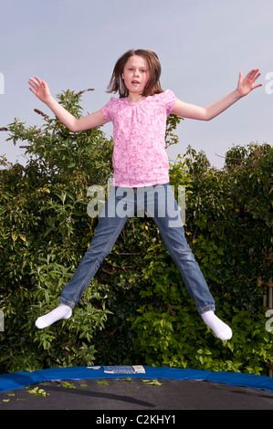 Ein MODEL Release Bild von ein neun Jahre altes Mädchen im Freien auf einem Trampolin im Vereinigten Königreich Stockfoto