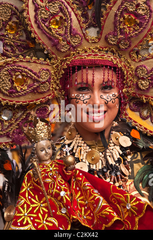 Ein Porträt einer Dame in Perlen Kostüm und Perlen Kopfschmuck hält ein Sto. Nino-Statuette. Stockfoto