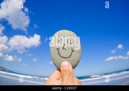 Weitwinkeleinstellung eines lächelnden Kieselsteins an einem Sandstrand. Stockfoto