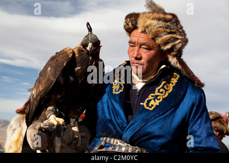 Mongolische kasachischen Eagle Hunter in traditioneller Tracht mit Kapuzen Eagle, Eagle Festival, Western Region, Mongolei Stockfoto