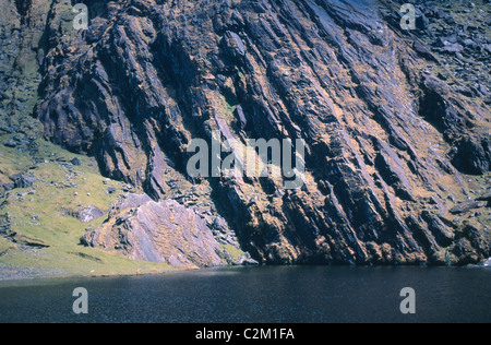 Gefaltete Sandsteinfelsen an einem See im Knockmoyle Coomavoher, Berg, County Kerry, Irland. Stockfoto
