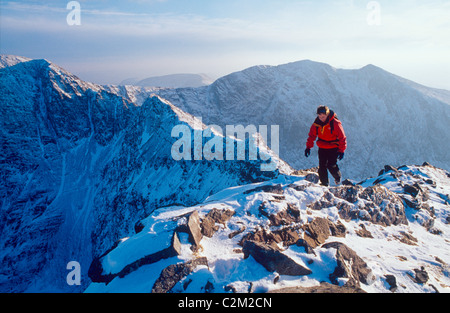 Winter Walker auf der Beenkeragh Ridge, mit den Carrauntoohil hinter sich. MacGillycuddy's Reeks, County Kerry, Irland. Stockfoto