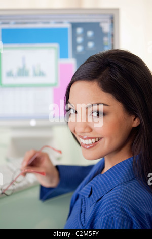 Lächelnd Hispanic Frau am Schreibtisch mit Computer-monitor Stockfoto