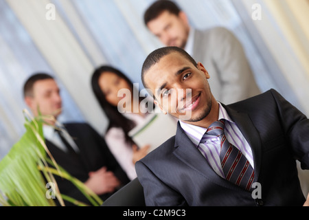Glücklich afrikanisch-amerikanischer Geschäftsmann mit seinem Team hinter Stockfoto