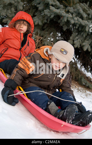 Jungen und Mädchen Alter 7 und 6 Winter Rodeln auf Schnee in Merriam Park. St Paul Minnesota MN USA Stockfoto