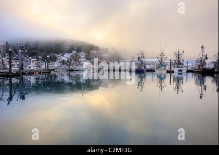 Morgennebel lichtet sich über kleine Bootshafen von Cordova, Alaska, USA. Ruhigen Hafen spiegelt Boote und ein kleines Fischerdorf. Stockfoto