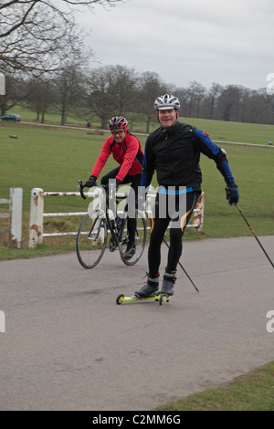 Ein Langläufer auf Straße Skates und ein Radfahrer trainieren im Richmond Park, Richmond, Surrey, UK. Stockfoto