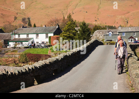 Grange, Cumbria, England, UK. Menschen, die über alte Dorf Brücke über den Fluss Derwent in Borrowdale im Lake District National Park Stockfoto