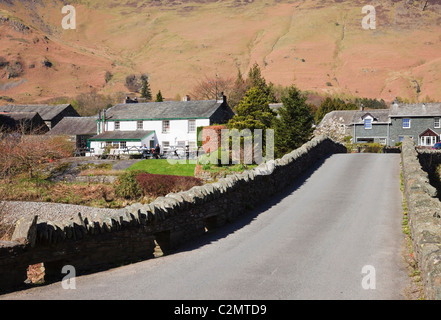 Blick auf ein Dorf entlang der alten Brücke über den River Derwent in Borrowdale im Lake District National Park. Grange, Cumbria, England, Großbritannien. Stockfoto