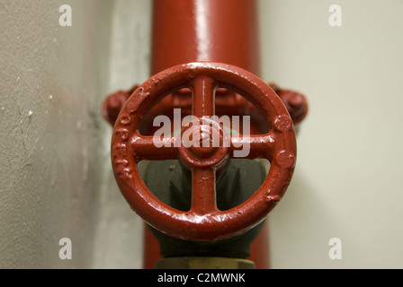 Ein rot lackiert kreisförmige Ventil im Brandschutzsystem Rohre von einem zivilen Gebäude Stockfoto