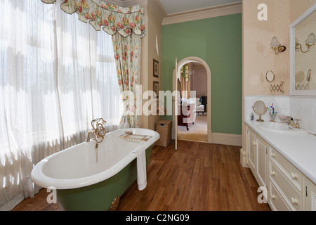 Bad mit roll-Top Badewanne, Holzboden ein Fenster drapiert Stockfoto