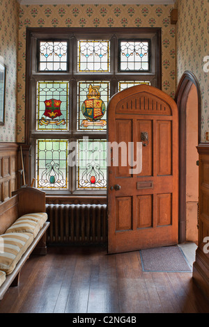 Eingangshalle und Buntglas-Fenster mit heraldischen Wappen, gewölbte Tür und hölzerne settke Stockfoto