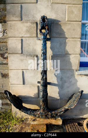 Alte Anker aus ein Boot oder ein kleines Schiff, lehnte sich gegen die vordere Wand eines Hauses in Mevagissey, Cornwall. VEREINIGTES KÖNIGREICH. Stockfoto