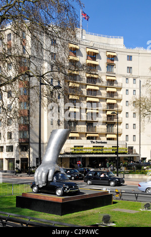 London street scene Dorchester Hotel Park Lane Mayfair hand auf Vintage Fiat Auto in der modernen Kunst Skulptur italienische Künstler Lorenzo Quinn England Großbritannien Stockfoto