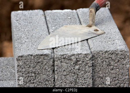 Maurerarbeiten Kelle auf einen Haufen von halben Zementblöcke Brise Bau einer Stützmauer Block im Vereinigten Königreich Stockfoto