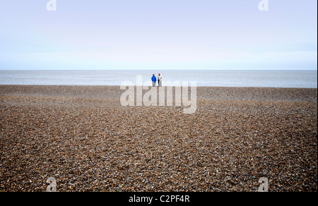 älteres Ehepaar allein auf einem Kiesstrand in Aldeburgh in Suffolk UK Stockfoto