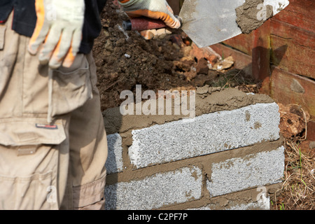 Maurer Bau einer Mauer Verlegung halbe Zementblöcke Brise Bau einer Stützmauer Block im Vereinigten Königreich Stockfoto