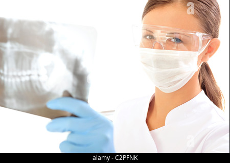 Zahnarzt tragen einen Mundschutz und Schutzbrille, befasst sich mit der Kamera, wie sie hält ein Röntgenbild. Horizontalen Schuss. Stockfoto