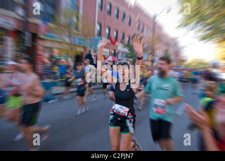 Frau läuft in Chicago-Marathon mit erhobenen Armen bei Meile 21 in Chinatown. Stockfoto