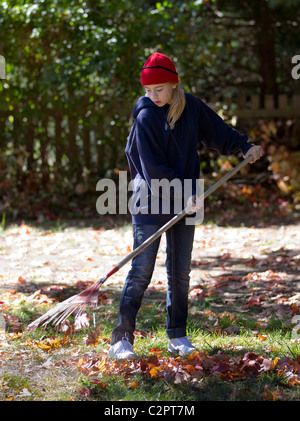 Ein Kind geht in den Hinterhof von Ihrem Haus Rechen Stockfoto
