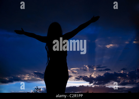 Frau silhouette genießen einen schönen Abend und öffnen Sie ihre Hände zum Himmel und saubere Luft atmen betrachten Gewitterwolken Stockfoto