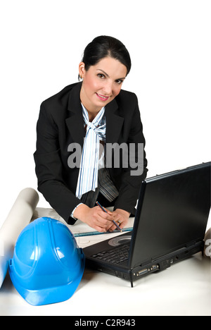 Architektin Frau trägt einen schwarzen Anzug, arbeiten in ihrem Büro auf Pläne und Laptop und lächelnd isoliert auf weißem Hintergrund Stockfoto