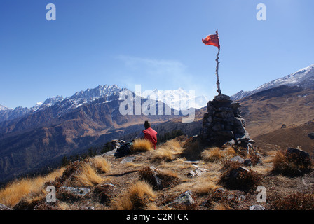 Garhwal-Himalaya, Indien: Ein Trekker sitzt unter einer Gebetsfahne nahe dem legendären Gesichtspunkt der Kuari-Pass. Stockfoto