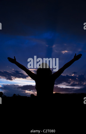 Frauen-Silhouette stehend mit offenen Händen nach dem Sturm Wolken Himmel und Regen zu genießen und zu meditieren Stockfoto