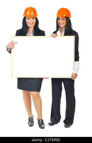 Gesamte Länge der beiden Architekten Frauen halten einen leeren Banner und orange Helmen isoliert auf weißem Hintergrund Stockfoto