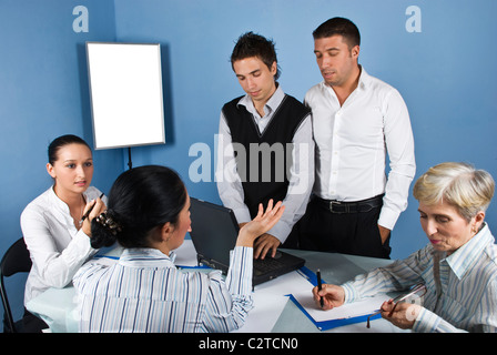 In der Mitte ein geschäftliches Treffen zwei Geschäftsleute einen Laptop verwenden und nach unten, während die Frauen, die ernstes Gespräch Stockfoto