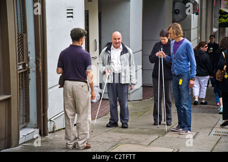 Begleitung eines Tauchlehrers, lehrt ein blinder Mann mit einem Blindenstock zwei junge Freiwillige zur Unterstützung der behinderter Menschen auf Fi Stockfoto