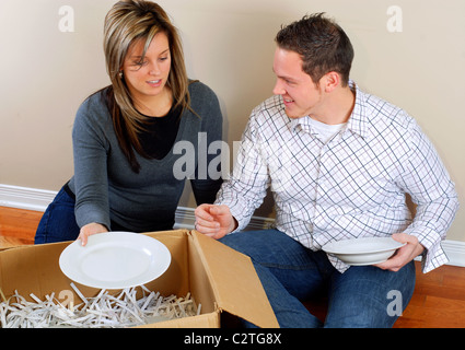 Junges Paar sitzt auf dem Boden Auspacken Boxen In ihrem neuen Zuhause Stockfoto
