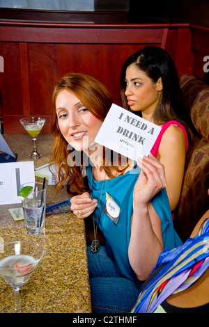 Speed dating Teilnehmer halten ein Zeichen signalisieren, dass sie benötigen, um ein anderes Getränk in einem California Restaurant serviert werden. Stockfoto