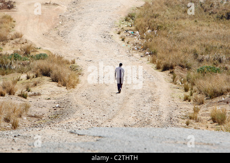 Ein afrikanischer Mann geht auf einer staubigen Straße in Kenia Stockfoto