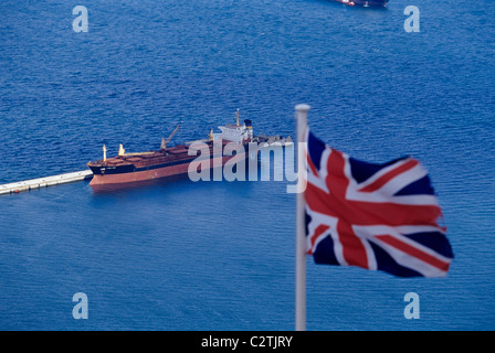 Ein Union Jack Schiff Flagge über Gibraltar Hafen mit einer Ladung im Hintergrund Stockfoto