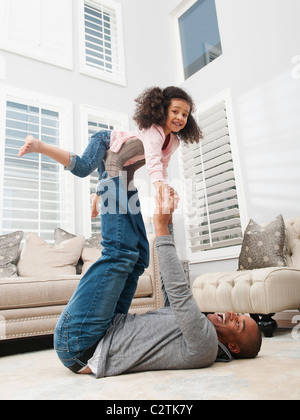 Anhebende Tochter Vater auf seinen Füßen Stockfoto