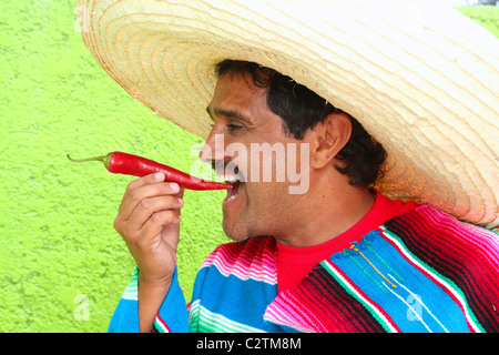 Mexikanische Mann Poncho Sombrero Essen roten Chili Paprika Mexiko Stockfoto