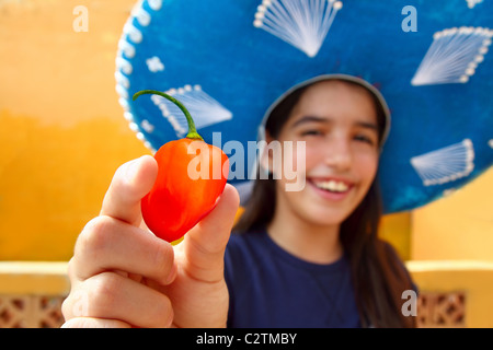 Mexikanisches Mädchen zeigen Habanero orange Chilischote mexikanischen Hut Stockfoto