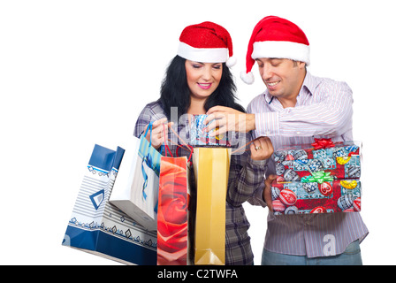 Paar mit Santa Hüte Lachen brachte Weihnachtsgeschenke und der Mann, der versucht, eine kleines Geschenk-Box in einer Einkaufstasche einzuführen Stockfoto