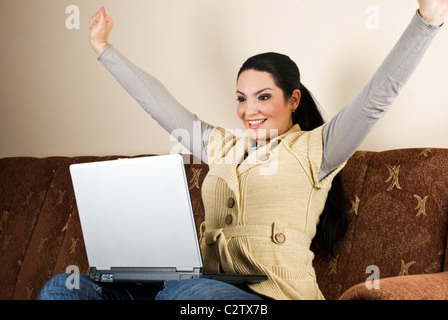 Jubelnd Frau mit Erfolg im Geschäft, sie sitzen auf der Couch im Wohnzimmer und mit laptop Stockfoto